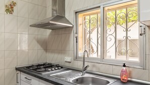A kitchen with a gas stove, stainless steel sink, and a window with decorative iron bars. - Holiday Home 'Cas Llimoner' close to the Sea with Terrace & Wi-Fi (Palma)