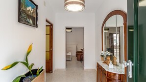 A hallway with a potted plant, a painting, a mirror, and a door leading to a room. - Holiday Home 'Cas Llimoner' close to the Sea with Terrace & Wi-Fi (Palma)