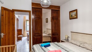 A bedroom with a bed, a wooden wardrobe, a nightstand, and a hanging light fixture. - Holiday Home 'Cas Llimoner' close to the Sea with Terrace & Wi-Fi (Palma)