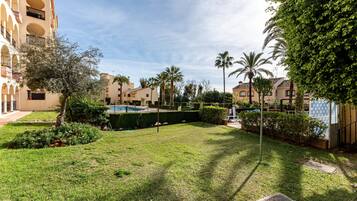 A courtyard with a swimming pool, palm trees, and a building with balconies.