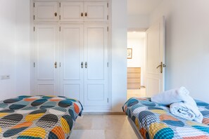 Une chambre avec deux lits, une armoire et une salle de bain visible à travers une porte ouverte.