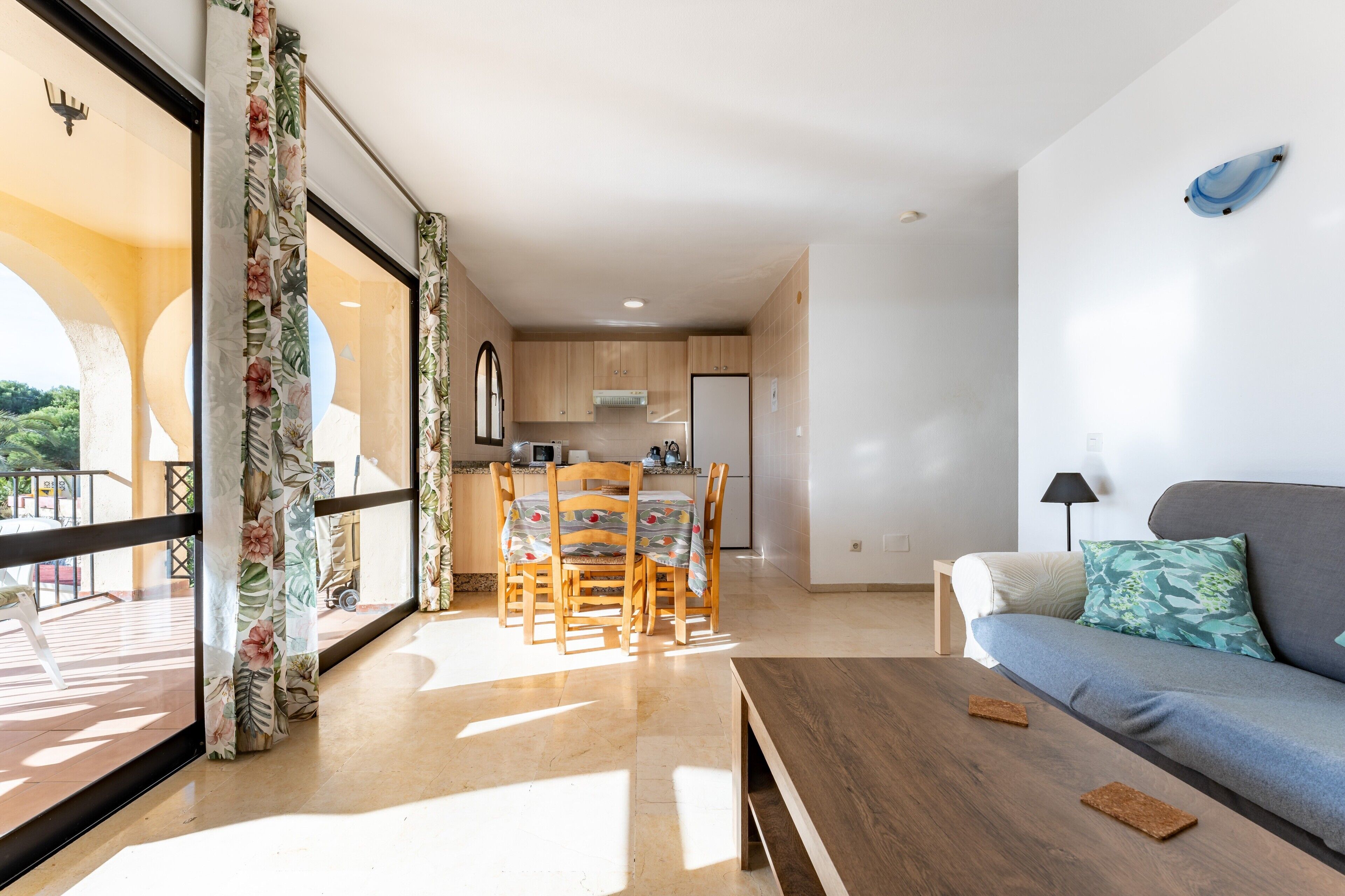 A modern living room with a sofa, a coffee table, and a dining area with chairs and a table.