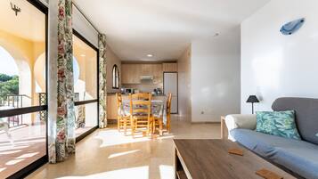 A modern living room with a sofa, a coffee table, and a dining area with chairs and a table.