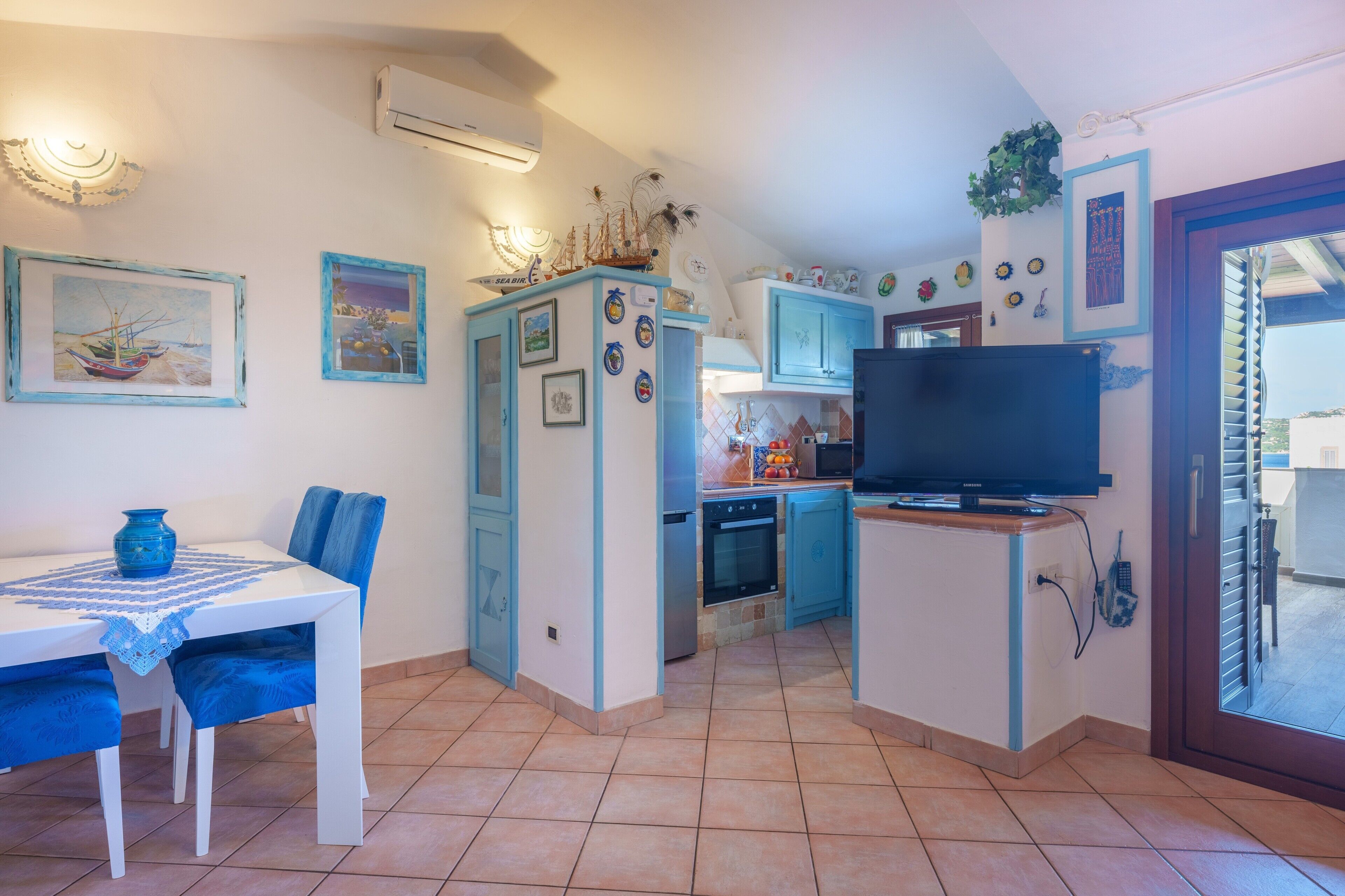 A compact kitchen with a TV, dining table, and chairs.