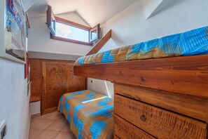 A bedroom with a bunk bed, wooden furniture, a window, and a door.