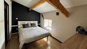Ein Schlafzimmer mit einem Bett, Holzbalken, einem Fenster und einem kleinen Tisch.