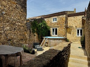 A stone building with a swimming pool, outdoor seating, and a staircase leading to the upper floor.