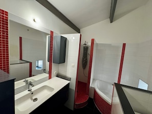 A modern bathroom with a large mirror, a sink, a shower, and a bathtub.