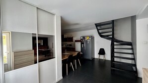 Eine moderne Küche mit einer schwarzen Wendeltreppe, einem Essbereich mit Stühlen und einer Kücheninsel.