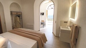 Une chambre avec un lit, une armoire, une salle de bain avec un lavabo et un balcon avec vue.