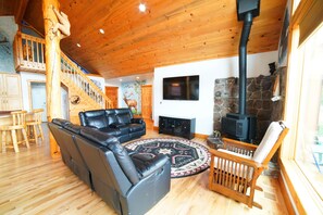 Cozy living area with a leather sofa, stone fireplace, and flat-screen TV.
