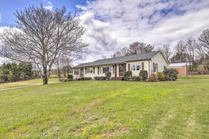 A single-story house with a front porch, surrounded by a grassy yard and a large tree. - Tasteful Country Home on 5 Acres ~ 3 Mi to Lake! (Westmoreland)