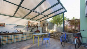 An outdoor kitchen area with a table, chairs, and a bicycle. - Holiday apartment with internet and air conditioning near the sea (Umag)