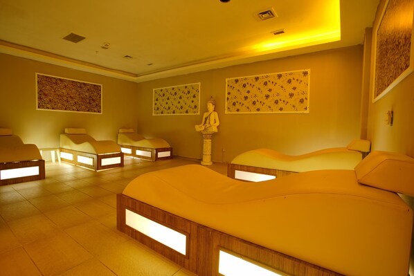 A room with multiple massage beds, a statue, and floral wall art.
