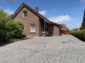 A brick building with a sloped roof, a small porch, and a paved driveway.
