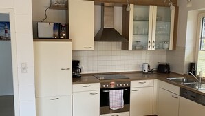 Una cocina moderna con armarios blancos, una campana de acero inoxidable y una encimera de madera.