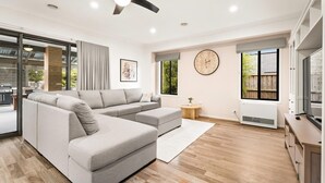 A modern living room with a sectional sofa, a clock on the wall, and a large window. - Boobook Retreat in Cowes (Cowes)