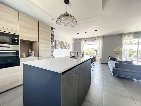 A modern kitchen with a central island, built-in appliances, and pendant lighting.