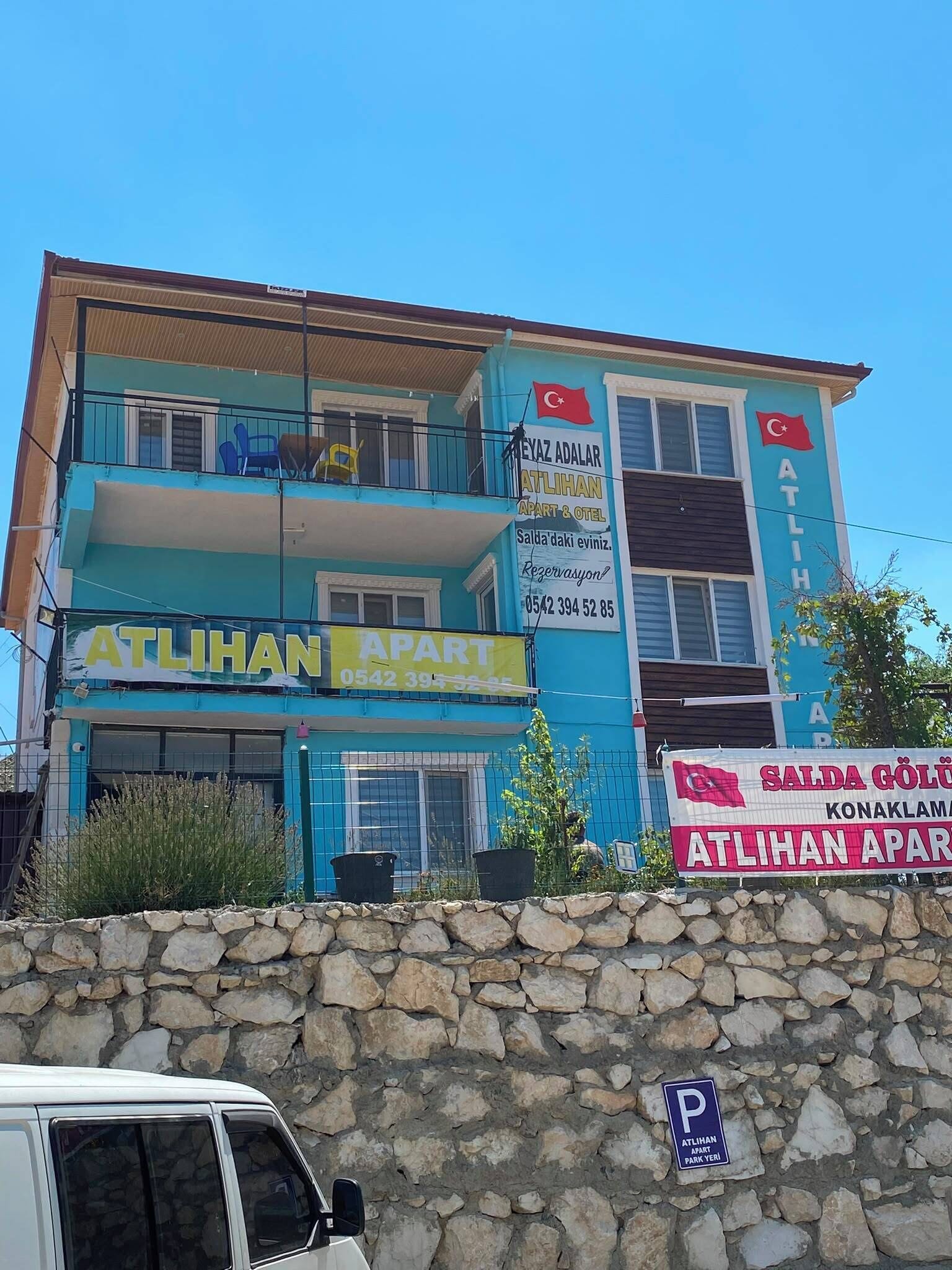 Um edifício de vários andares com placas indicando 'ATLILHAN APART' e 'SALDA GOLU KONAKLAMA'.