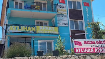 Um edifício de vários andares com placas indicando 'ATLILHAN APART' e 'SALDA GOLU KONAKLAMA'.