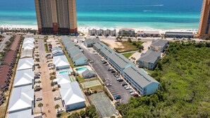 A resort with multiple buildings, a pool, and a beach view.