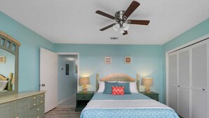 A bedroom with a bed, nightstands, a dresser, a ceiling fan, and a closet.