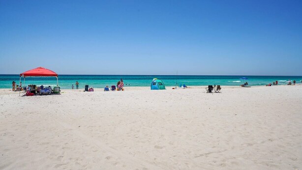 A beach with a red tent, a blue tent, and several beach chairs.