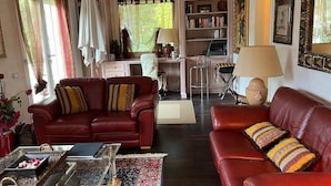 A living room with a red leather sofa, a glass coffee table, and a bookshelf. - Villa MIMA with garden on two floors, 100 m from the sea. (Milano Marittima)