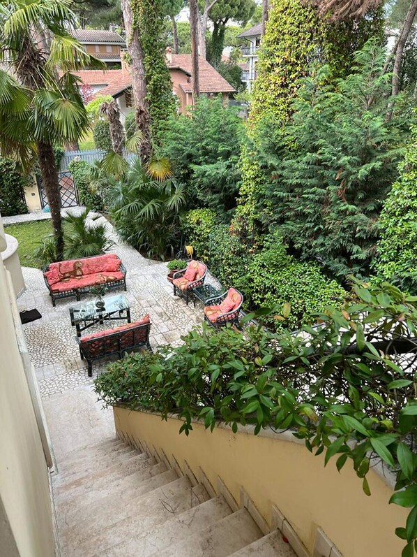 A courtyard with outdoor seating, a staircase, and lush greenery.