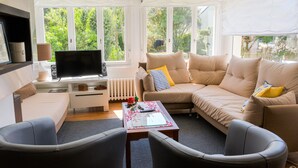 A cozy living room with a sofa, armchairs, a coffee table, and a TV. - 450 m from the beach – House for 6 – Garden & BBQ (Treffiagat)