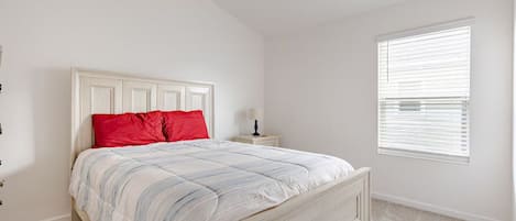 Quarto com cama, mesa de cabeceira, janela com persianas e ventilador de teto.