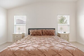 A bedroom with a bed, two bedside tables, and a window.