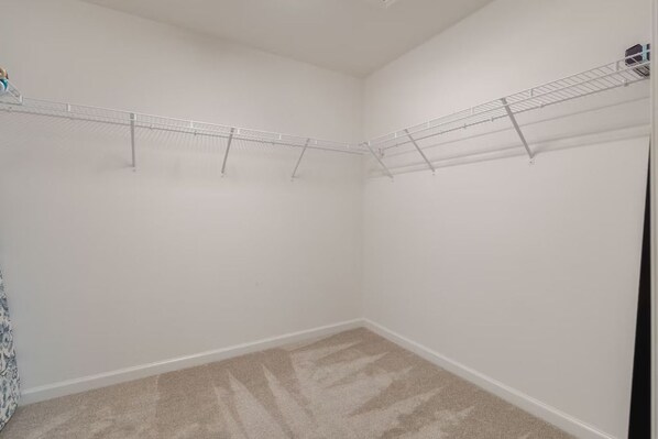 A room with a beige carpet, white walls, and a metal drying rack.