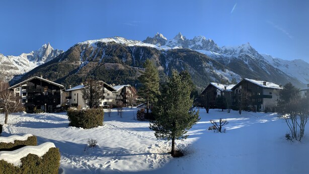 Paisatge cobert de neu amb edificis i muntanyes al fons.