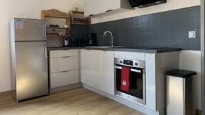Una cuina moderna amb nevera d'acer inoxidable, forn integrat, cafetera i microones.
