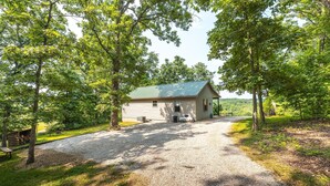 A rustic cabin with a gravel driveway, surrounded by trees and a view of the landscape. - Elevated Farm Cabin | River Views & Access, Hot Tub & Thoughtful Finishes (Steelville)