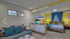 Quarto moderno com cama, mesas de cabeceira e televisão.