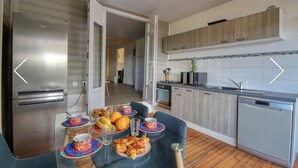 Cozinha moderna com eletrodomésticos de aço inoxidável, armários de madeira e um espaço de jantar com mesa posta para o café da manhã.