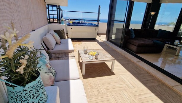 A modern outdoor living area with a sofa, a coffee table, and a hot tub. - Solbelli Oceanfront Penthouse | Jacuzzi (Mijas Costa (Riviera del Sol))