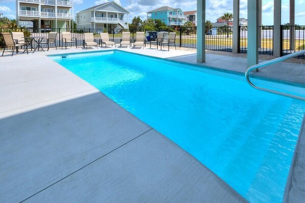 A swimming pool with lounge chairs and a view of nearby buildings.