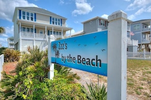 A sign for 'Luz's by the Beach' with a view of a beachfront property.