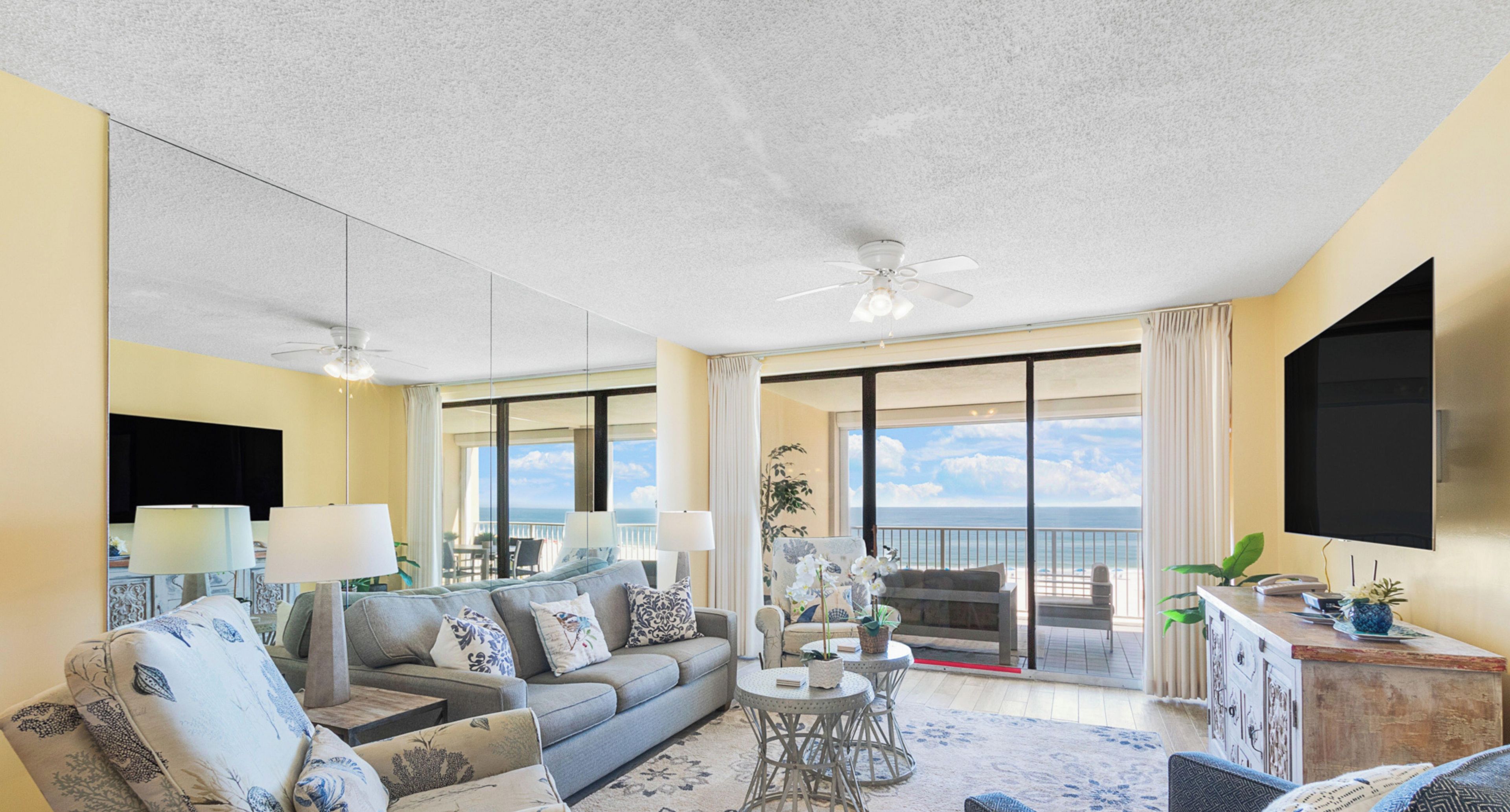 Un vaste espace de vie comprenant un canapé, des fauteuils, une table basse et un balcon avec vue.