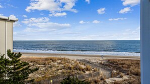 A beach view with a clear sky, a sandy beach, and a wooden fence.