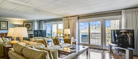 A spacious living room with a large sofa set, a coffee table, and a television.
