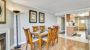 A dining area with a wooden table and chairs, a floor lamp, and two framed pictures on the wall.