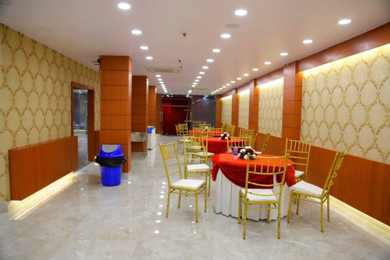 A banquet hall with rows of tables and chairs, a trash bin, and a stage area.