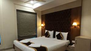 A hotel room with a large bed, two bedside tables, a wardrobe, and a ceiling fan. - The Panash Hotel & Banquets (Kolkata)