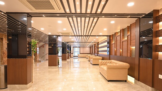 A modern hotel lobby with a polished marble floor, leather seating, and a ceiling with linear lighting fixtures. - The Panash Hotel & Banquets (Kolkata)