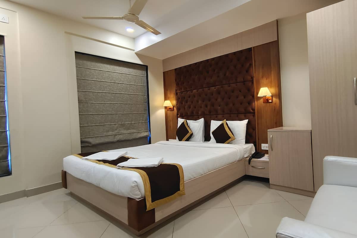 A modern hotel room with a large bed, a wardrobe, a desk, and a ceiling fan.