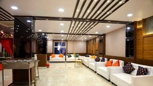 A modern hotel lobby with white sofas, a reception desk, and a large window. - The Panash Hotel & Banquets (Kolkata)